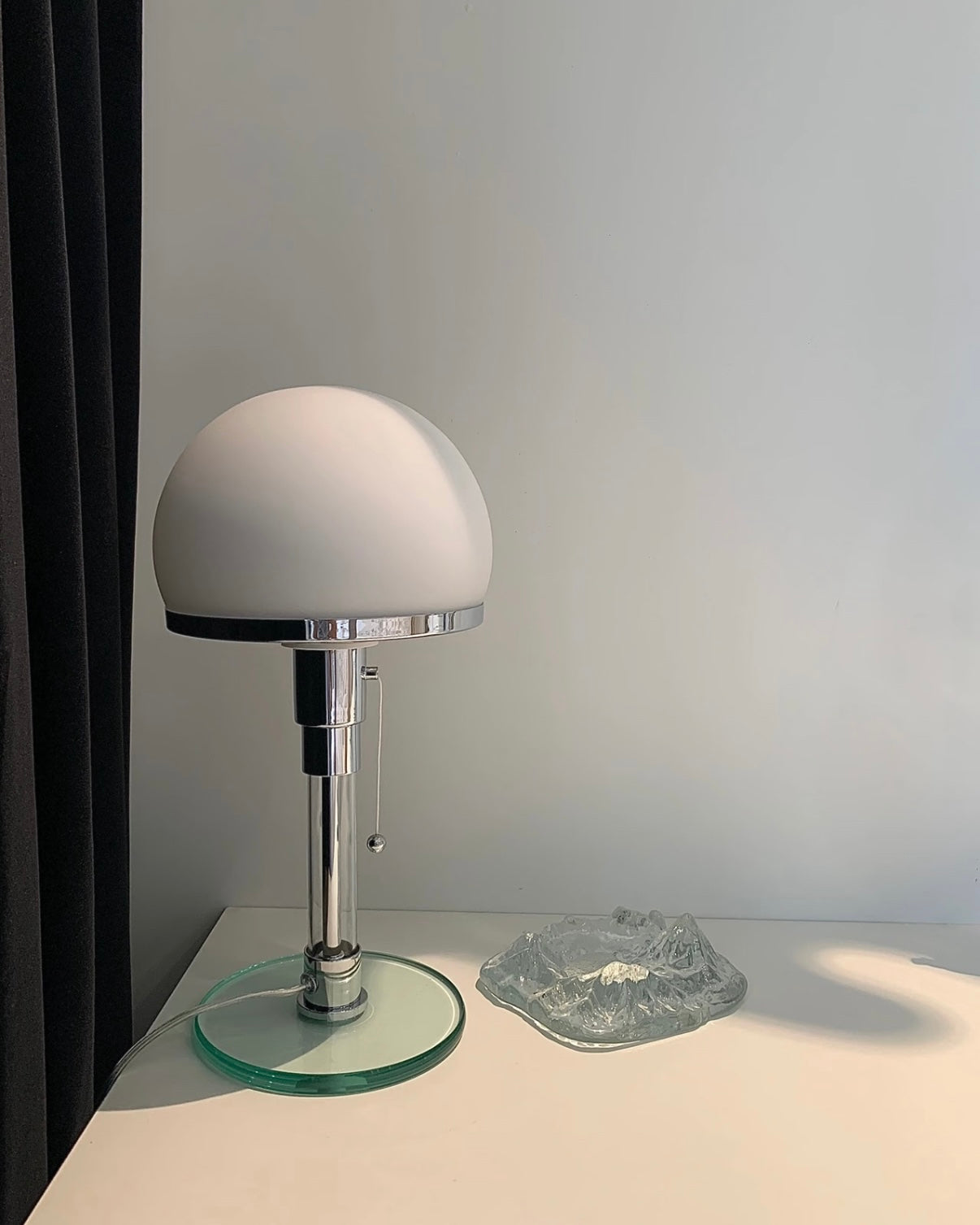 Chrome dome table lamp with glass base styled in café inspired setup with desserts nearby.