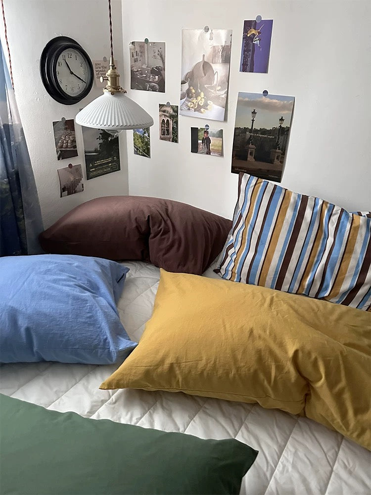 Mustard, green and blue pillowcases sit in front of mocha and striped designs.