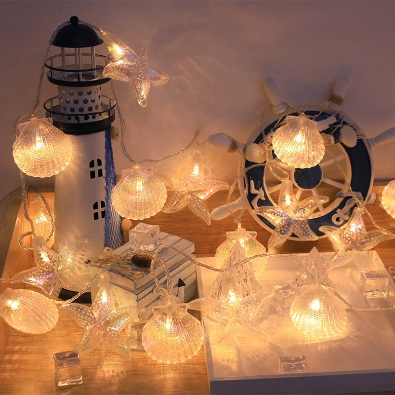 Decorative string lights with nautical-themed decorations on a wooden surface.