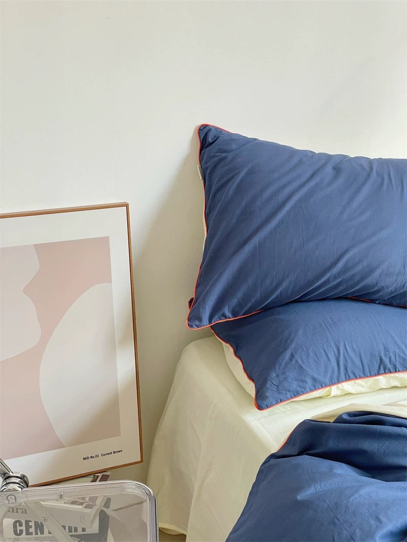 Blue pillows on a bed with a framed picture on the wall.