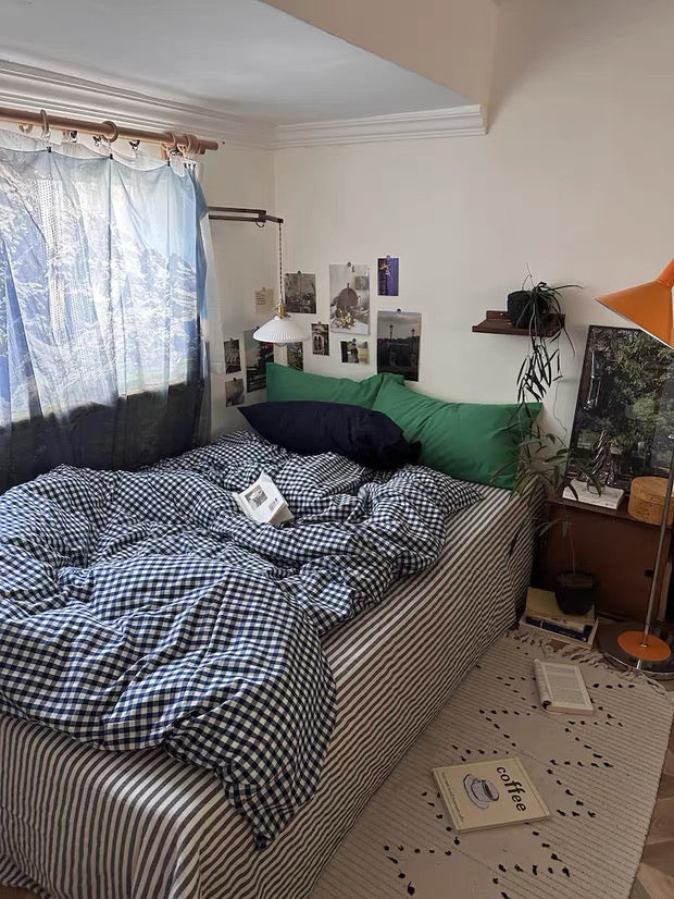 Room with a bed, checkered blanket, and various items on a shelf.