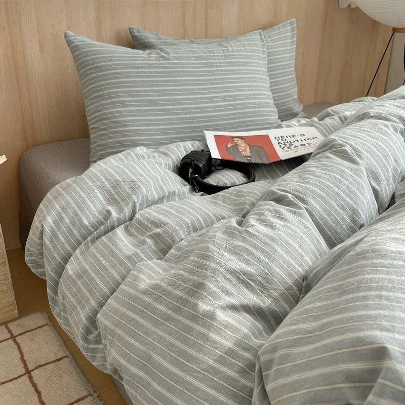 Striped bedding set on a bed with a wooden headboard