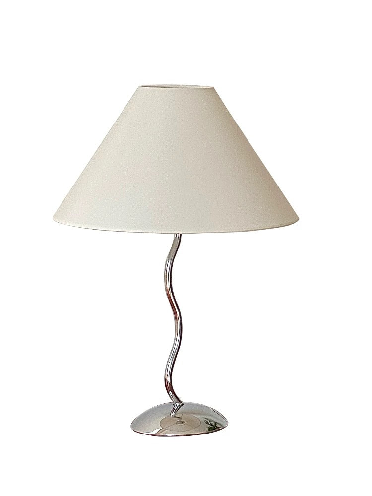 Table lamp with a white shade and curved metal base on a white background
