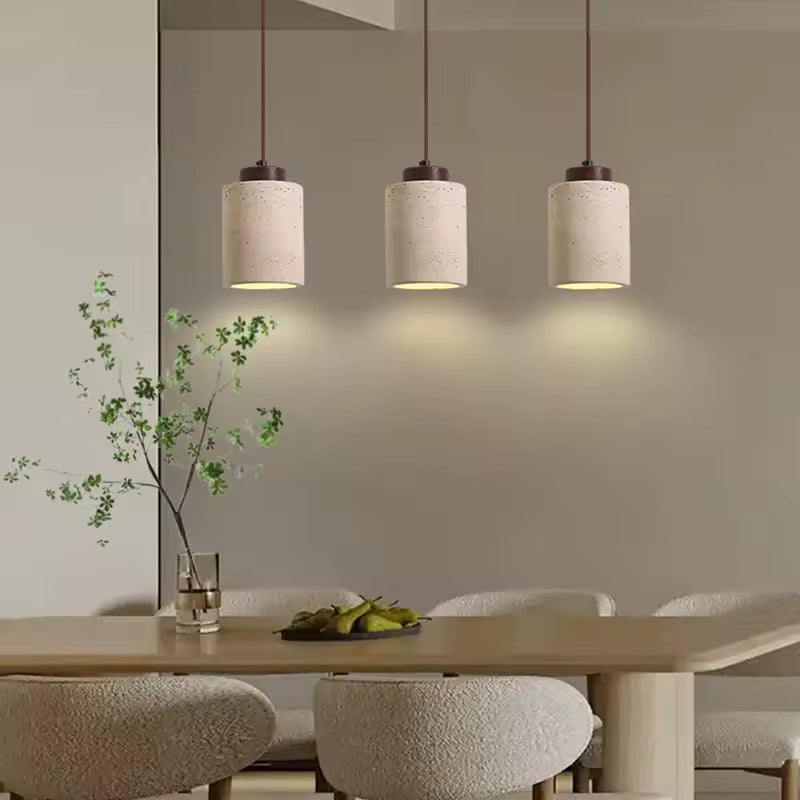 Organic modern hanging lamp with stone texture styled above kitchen island and neutral furniture.