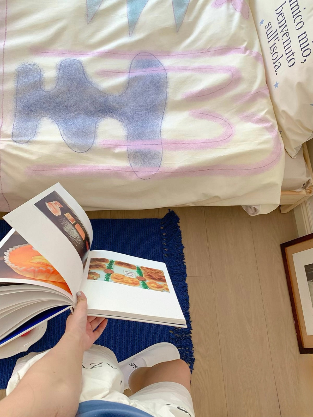 Close view of a blue shape and pink outlined cup on the pastel cover beside an open book.