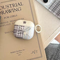 White earphone case with plaid design on a vintage book