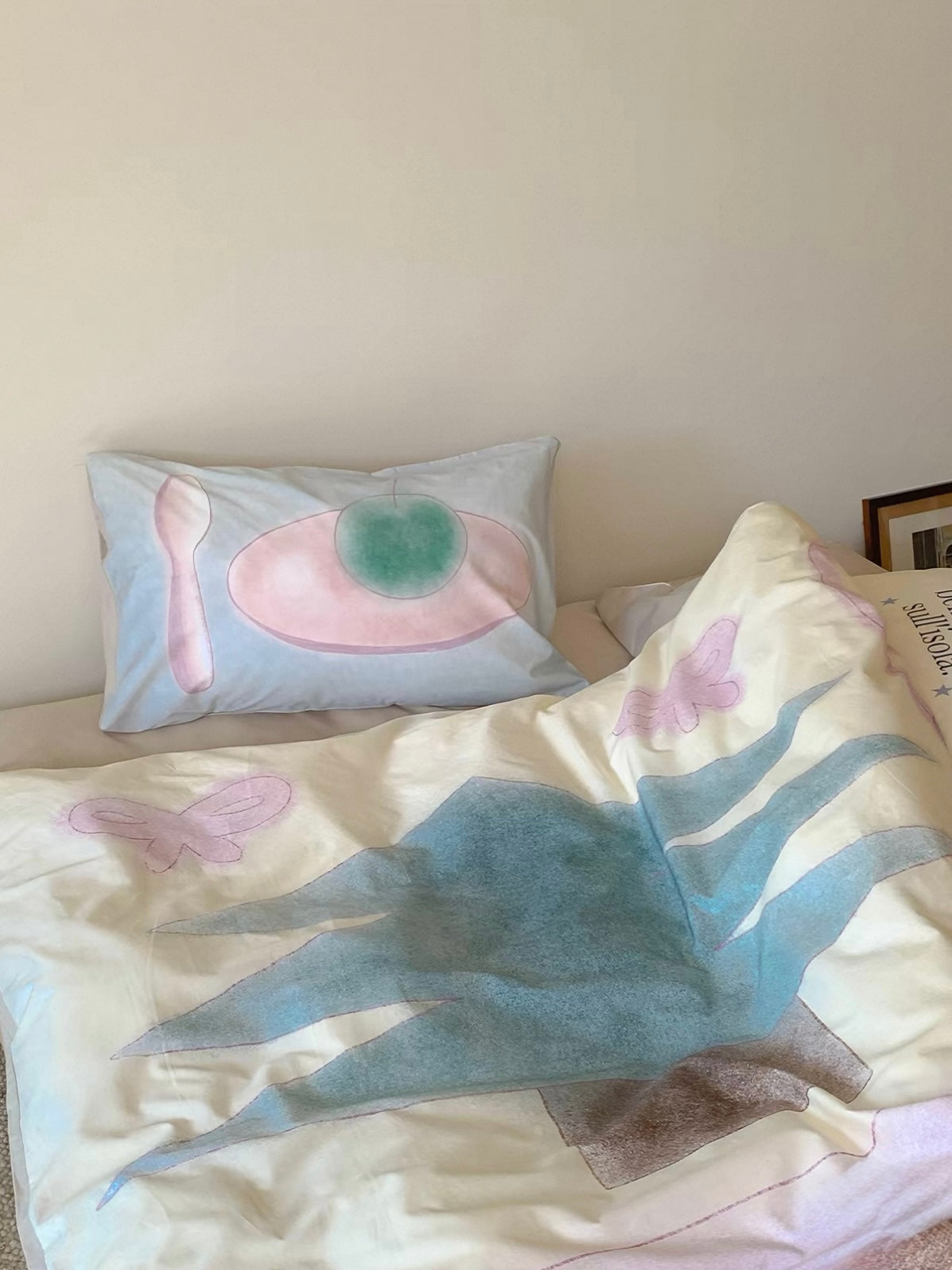 A rumpled pastel duvet cover beneath the illustrated pillowcase at the head of the bed.