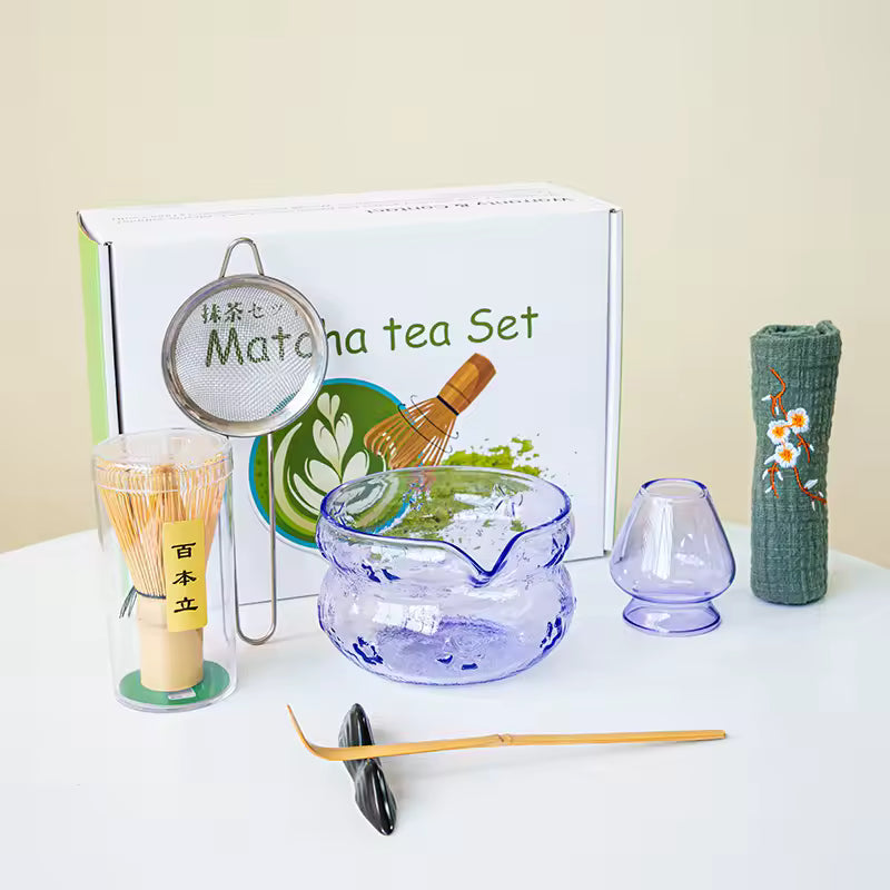 Matcha tea set with various tools and a branded box on a white surface.