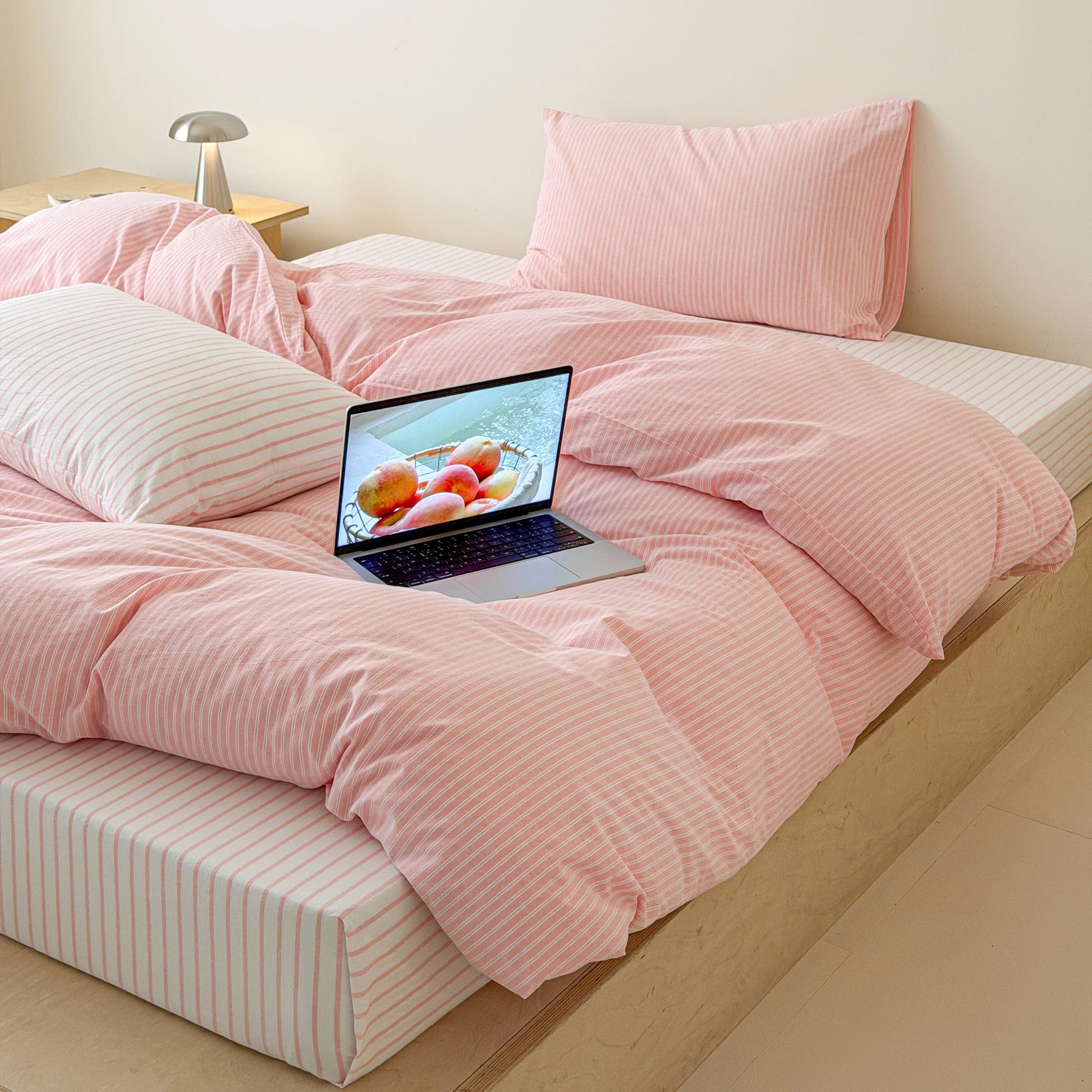 Pink striped bedding set creating calm minimalist interior with breathable cotton fabric and layered comfortable appearance.