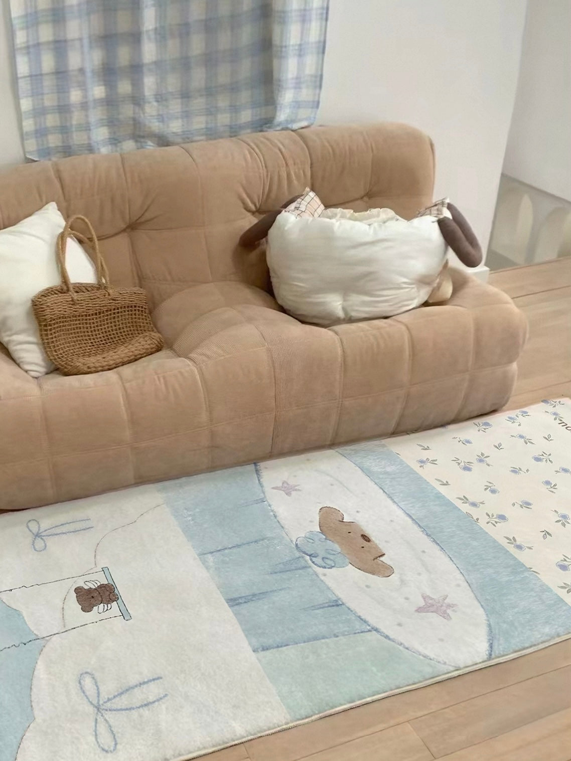 A pastel runner rug in pale blue and cream lies in front of a tan sofa, with illustrated panels.