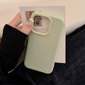 Light green phone case held by a hand with a blurred background