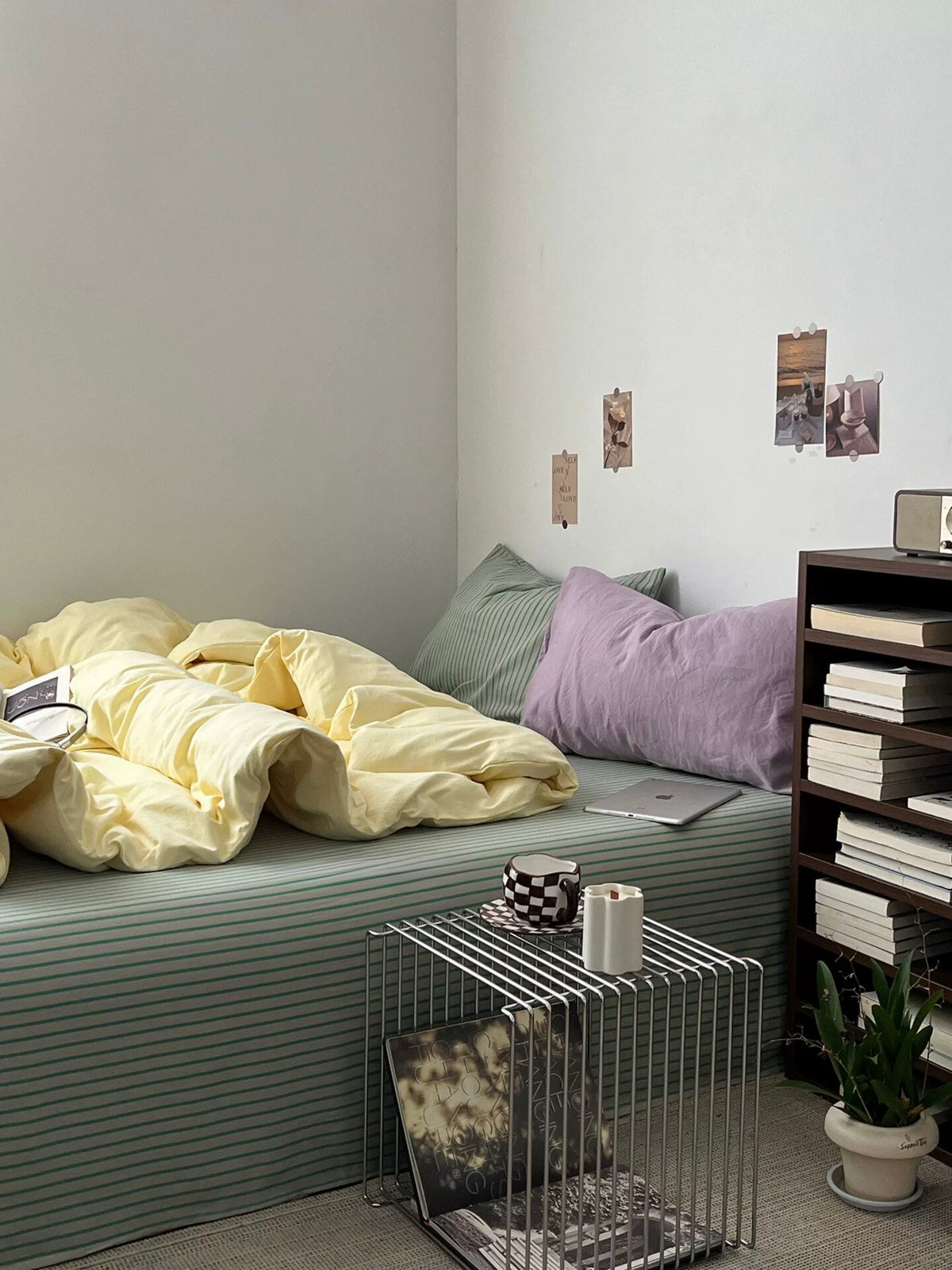 Yellow sage duvet cover beside dark bedside furniture in a pastel bedroom