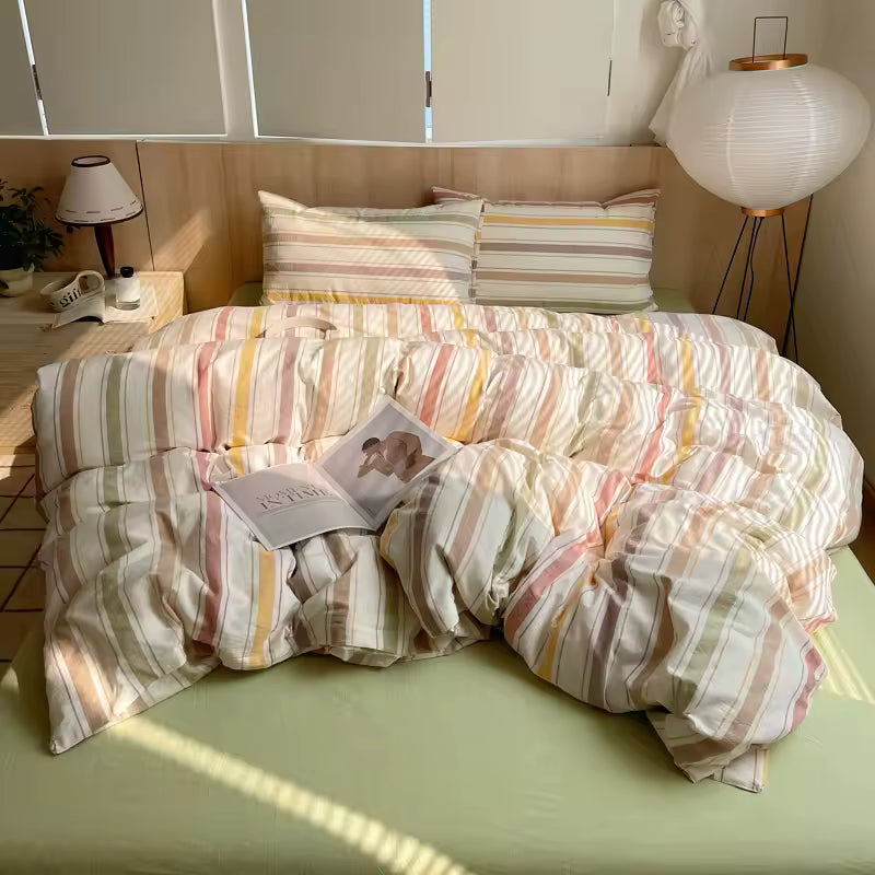 Bed with striped bedding and pillows in a room with lamps and cabinets.