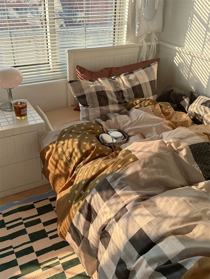 Bedroom with plaid bedding and a window with blinds