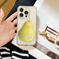Phone case with a pear design held by a hand, with a blurred background of a table setting.