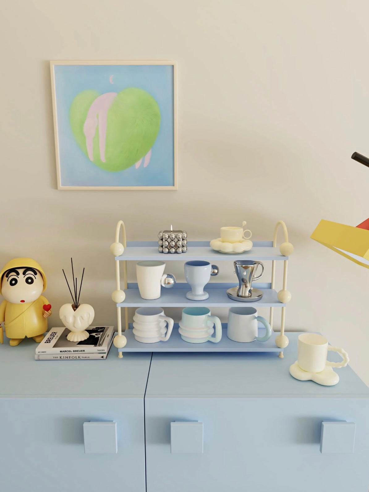 Blue perfume organizer shelf with cream sides stands on a desk with cups and saucers on its open levels.
