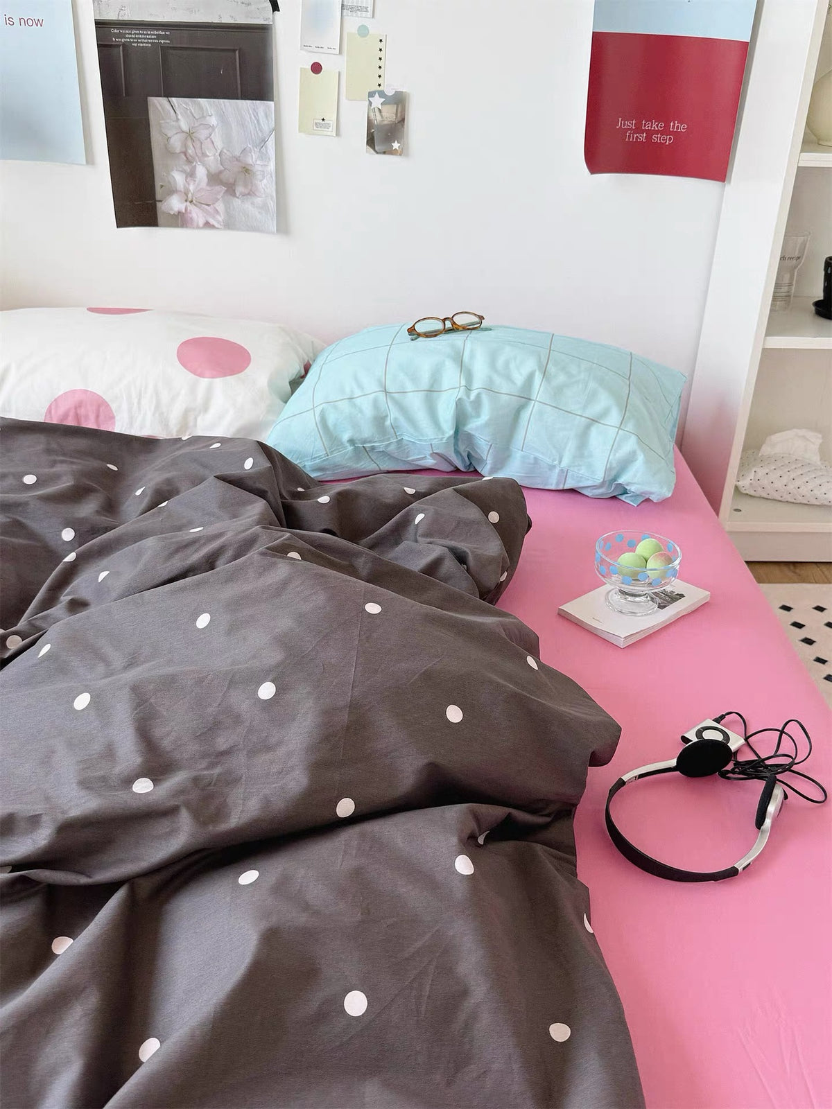A pink bedding set pairs a blue checked pillow with a white pillow covered in large pink dots.