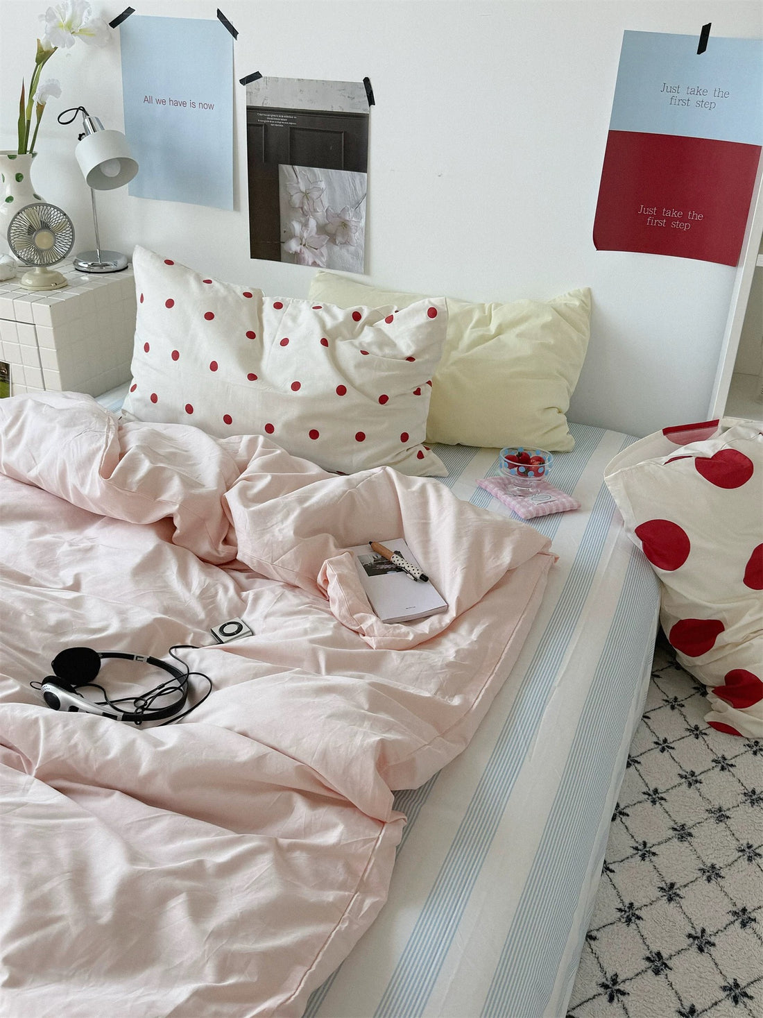 Preppy polka dot bedding set with a pink duvet cover, red and dotted pillows, and a blue striped sheet.