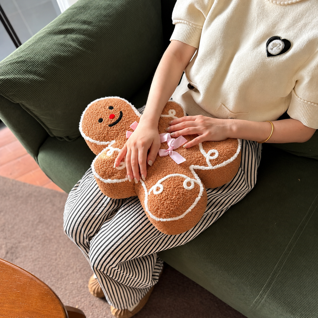 Gingerbread man, snowman and gingerbread house Christmas pillows arranged together on a green sofa