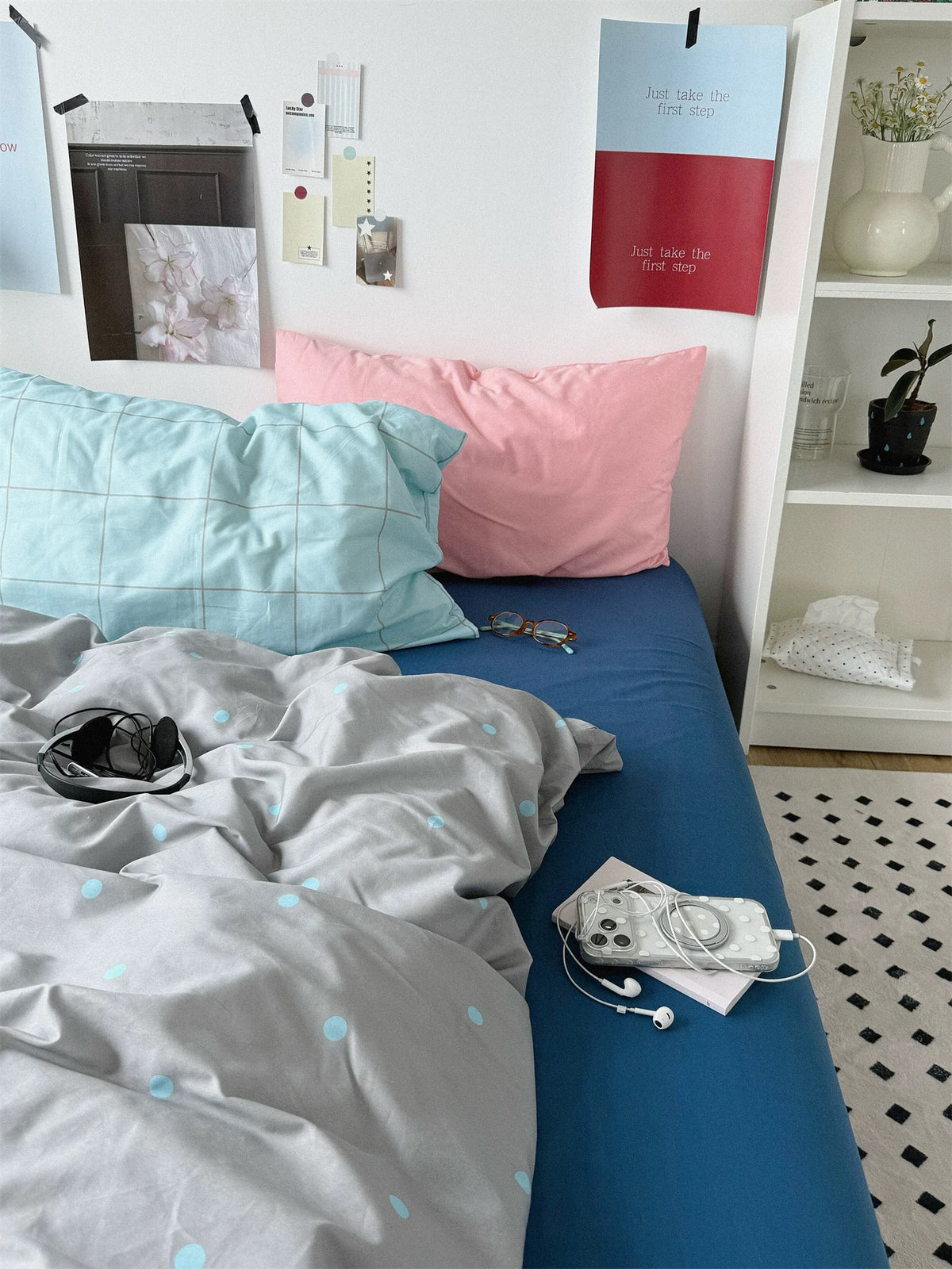 Pink and blue check pillowcases with the gray dotted cover draped across a blue sheet.