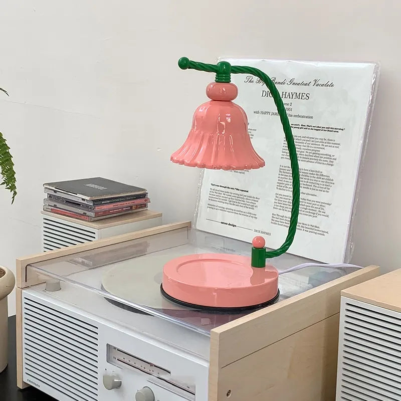 Pink candle warmer lamp with a scalloped shade suspended above a round matching pink base.