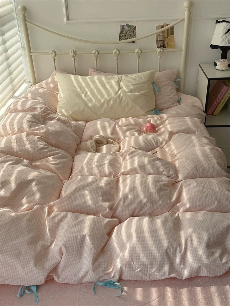 Bed with pink comforter and pillows in a bedroom setting