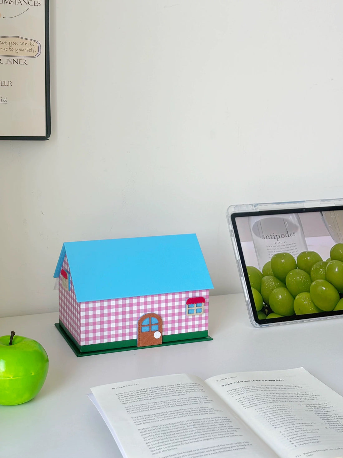 Pink gingham house shaped tissue box cover with blue roof on a white cabinet