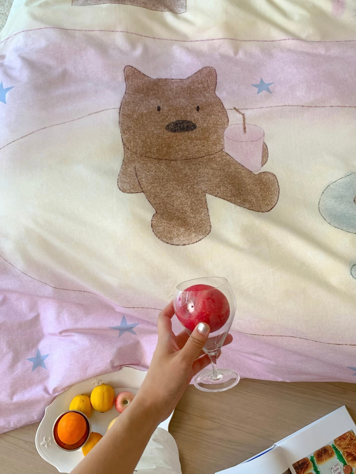 Close view of the brown teddy bear motif on the pale pink and cream cover.