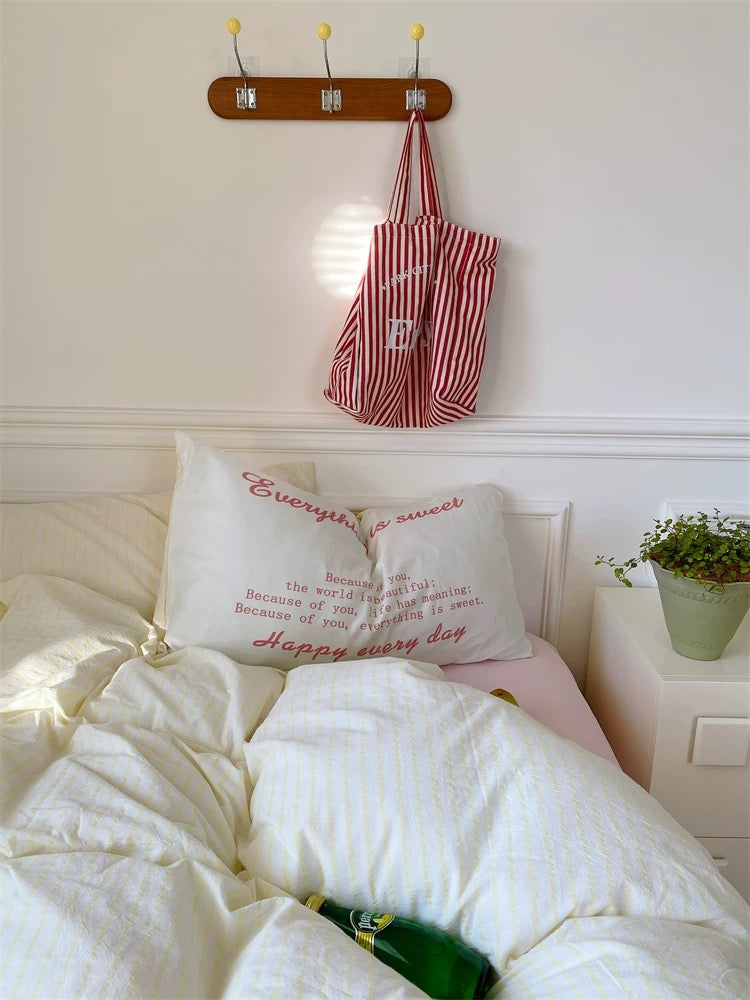 Bedroom with a pillow and striped bag on a hook above the bed