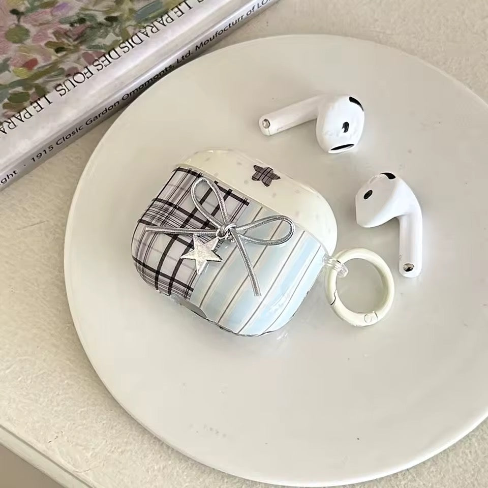White AirPods case with plaid design and keychain on a white plate