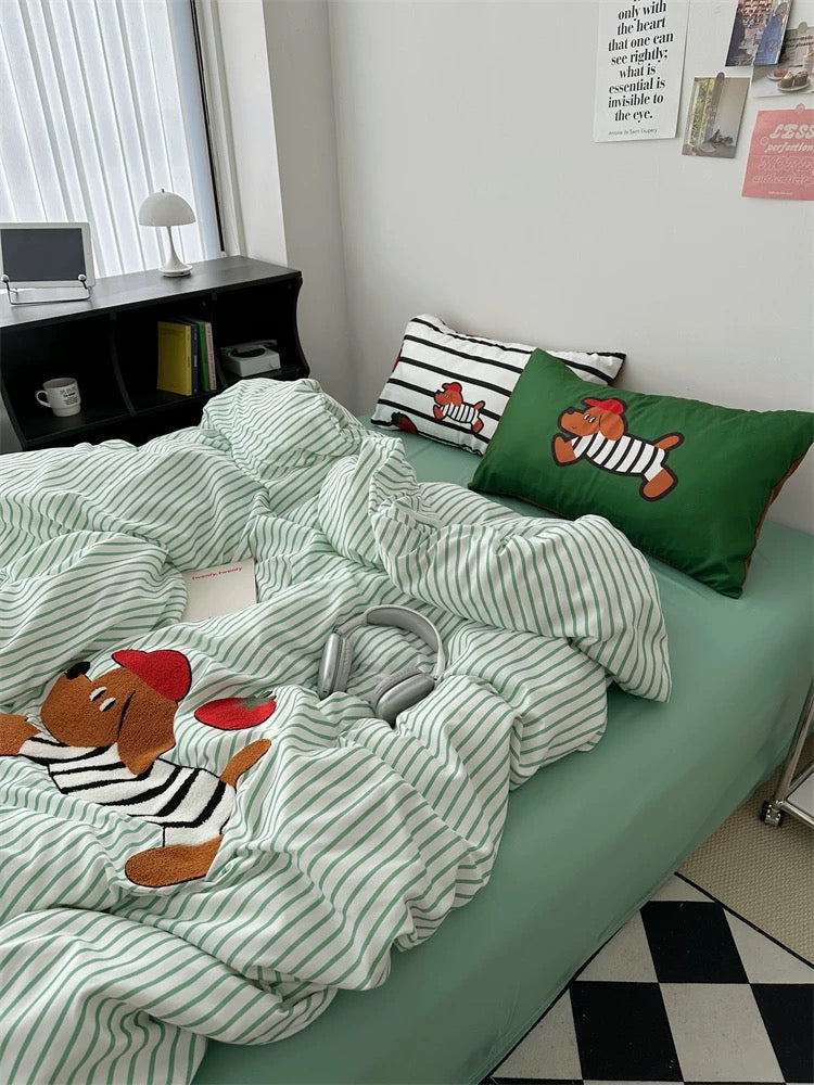Bed with green and white striped bedding featuring cartoon dog characters, in a room with a desk and window.
