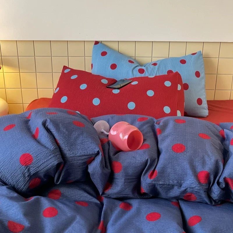 Blue red polka dot duvet cover displayed on cozy bed with pillows in college dorm