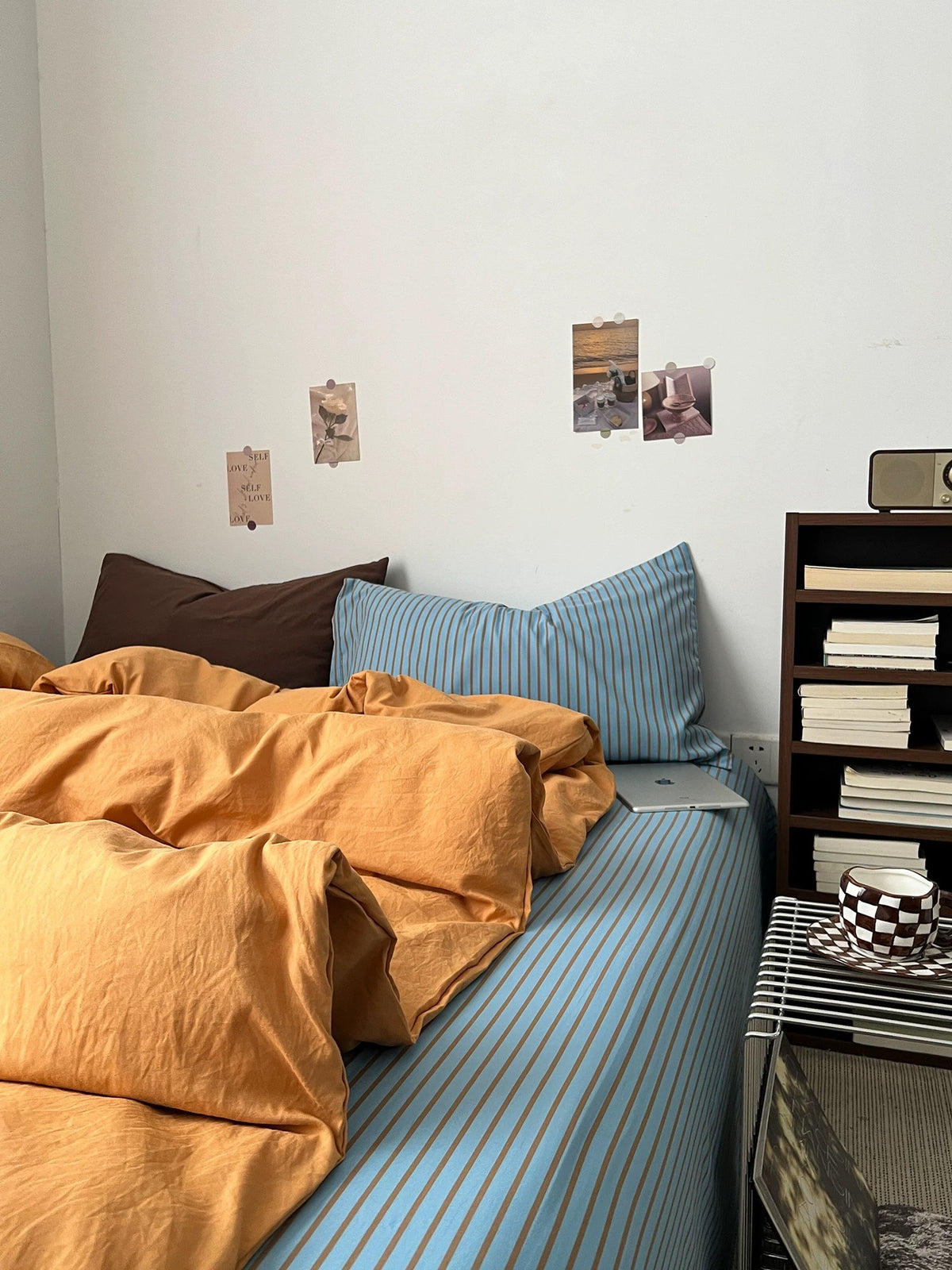 Orange and blue bedding seen from the bed edge with the striped sheet visible