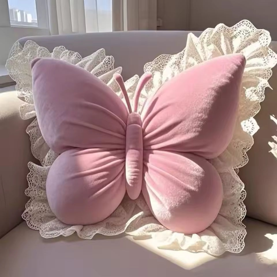 Pink butterfly-shaped pillow on a decorative cushion with lace trim.