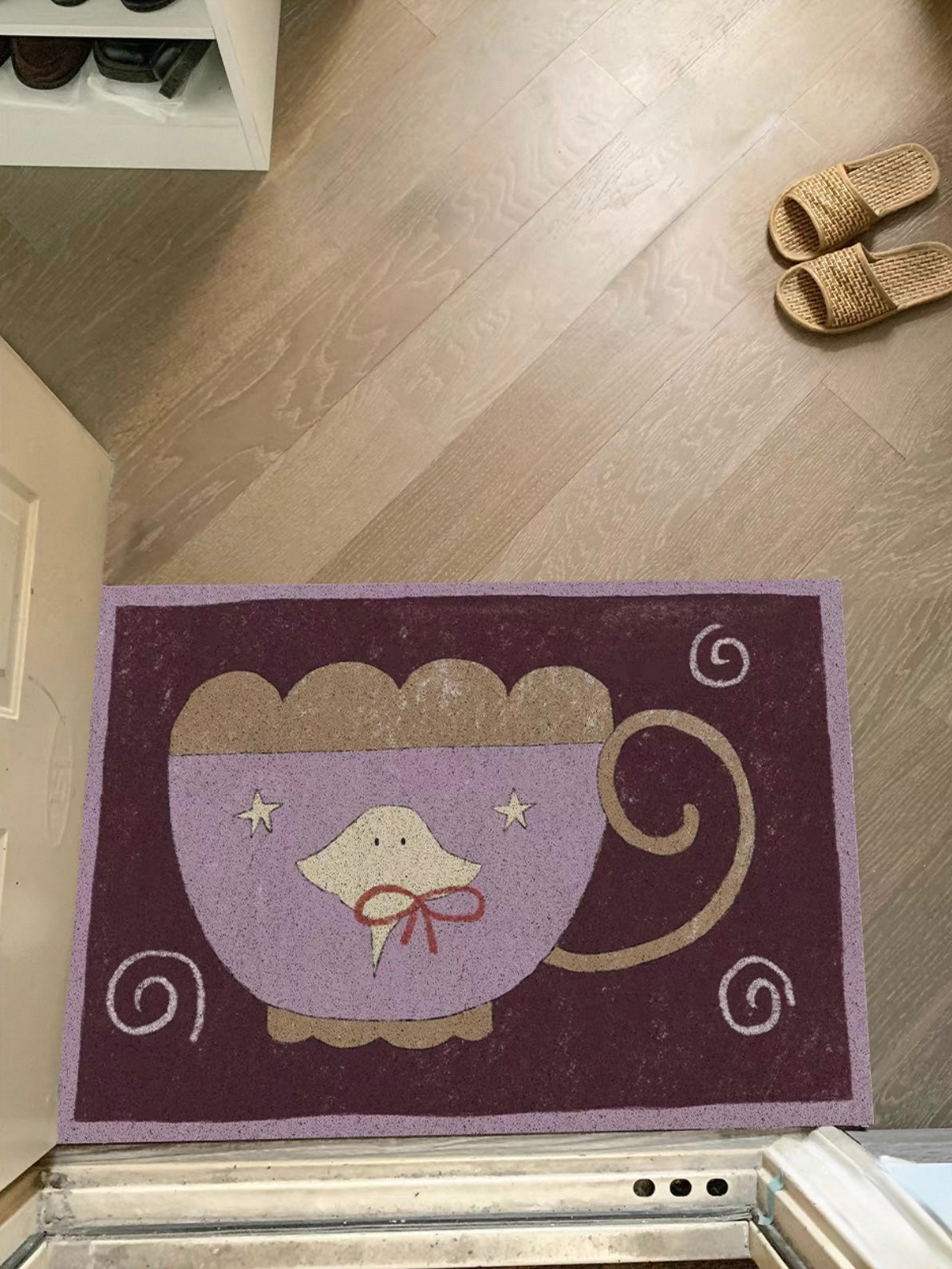 A purple jellyfish rug lies flat with a lilac cup, curled handle and pale spiral details visible.
