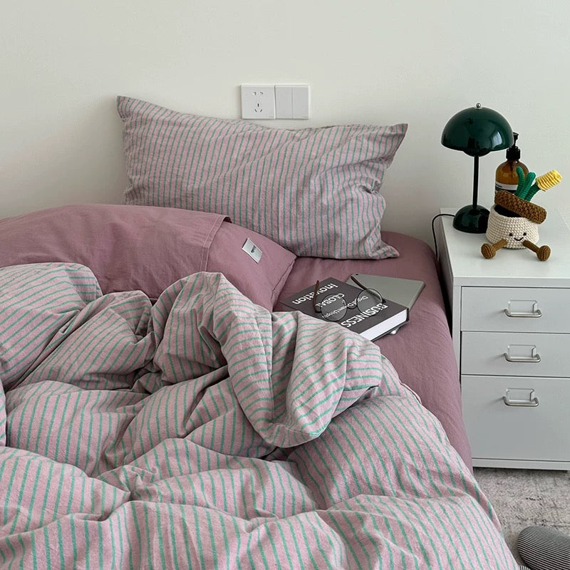 Bed with pink and white striped bedding in a bedroom setting.