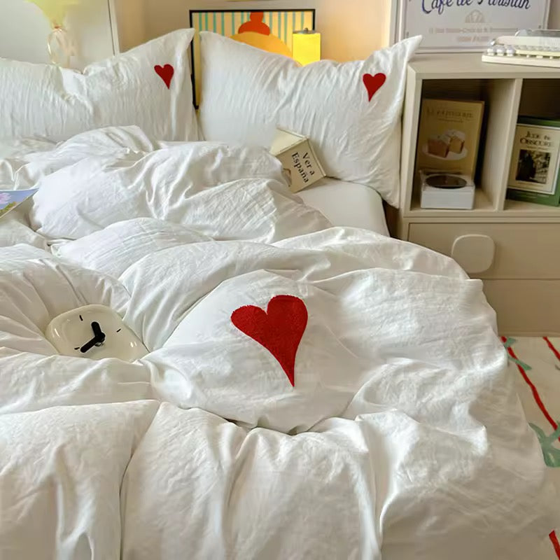 Close-up of heart embroidery detail on white cotton pillowcase.