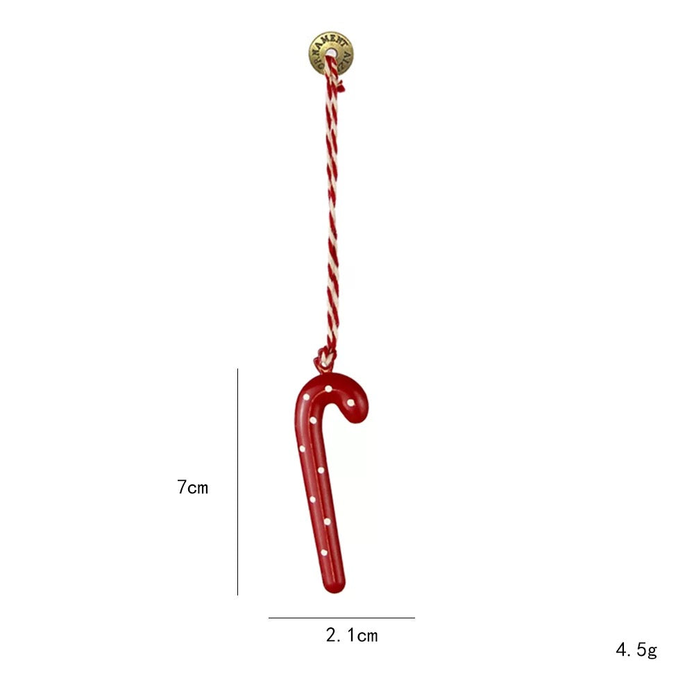 A red candy cane Christmas ornament has small white dots and a twisted red and white hanging cord.