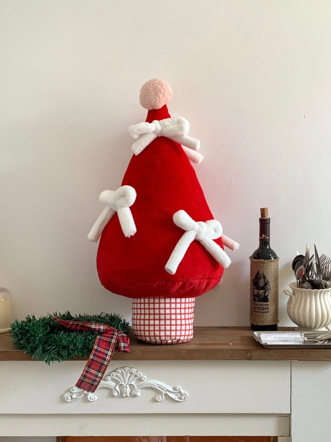 Christmas tree pillow with plush white bows styled beside a Christmas tree
