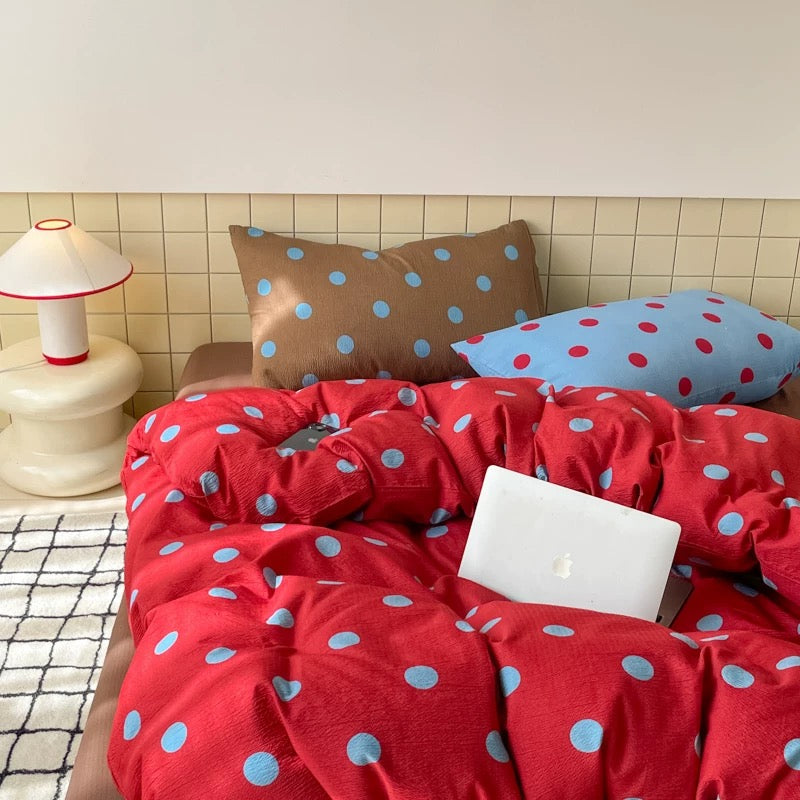 Red blue polka dot bedding set styled on preppy dorm bed with pillows natural light