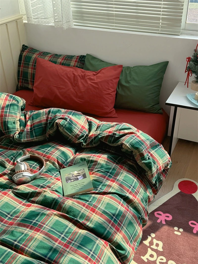 Plaid bedding with red and green colors on a bed in a room.