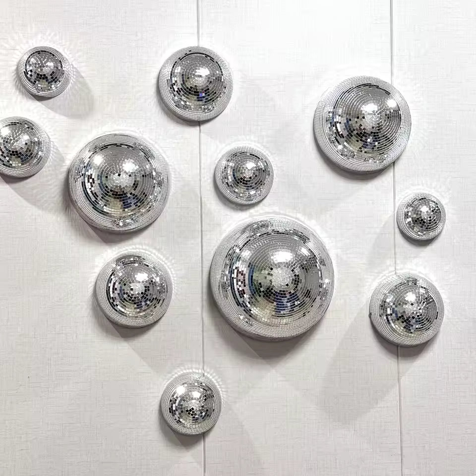 Decorative silver disco balls on a white wall with a framed picture below.