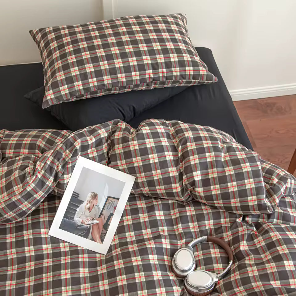 Plaid bedding set on a bed with a photo and headphones on top