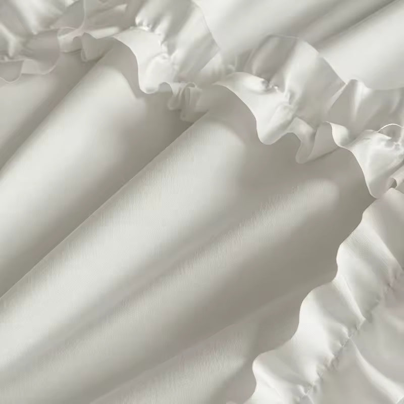 Luxury white ruffle comforter set shown on a dark wood bed frame.