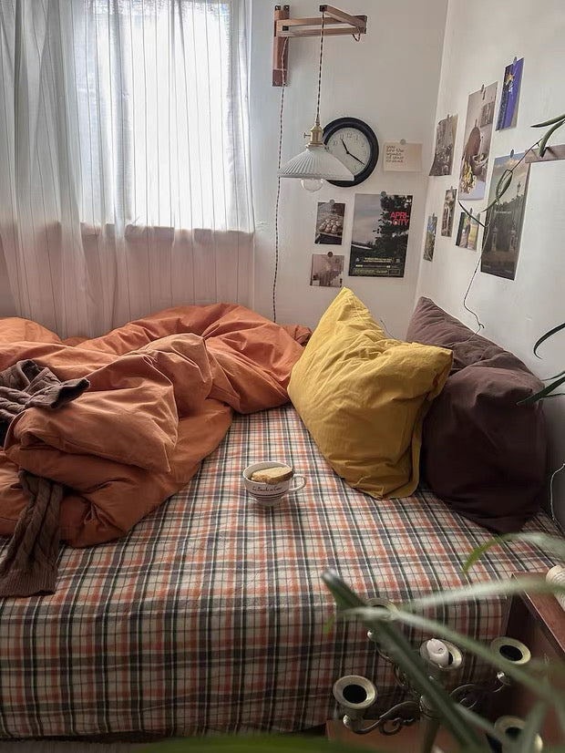 Rust orange duvet cover layered on plaid bedding for cottagecore bedroom and vintage room styling.