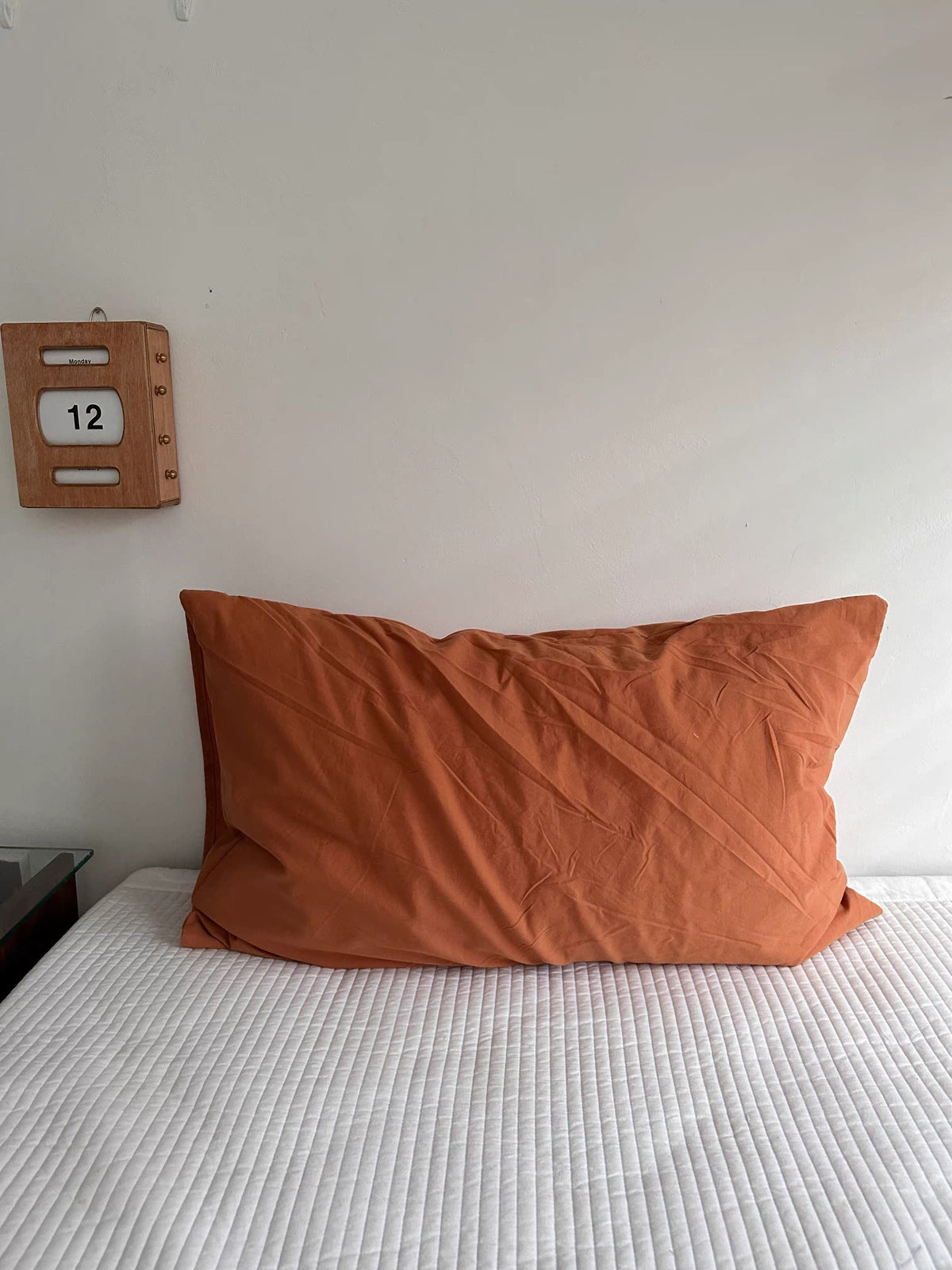 A rust orange pillowcase has a plain surface with visible fabric folds.