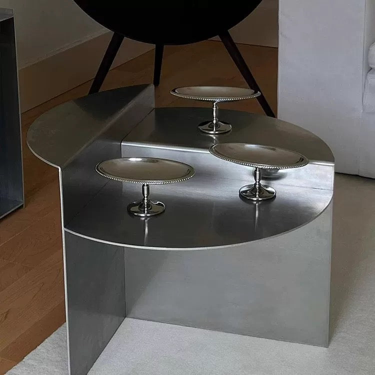 Round stainless steel coffee table with geometric platform creating architectural focal point for contemporary home decor spaces.