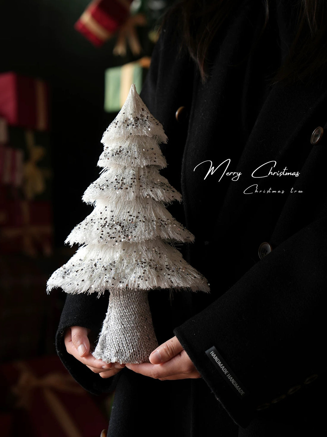A sequin Christmas tree with white fringed tiers and silver accents is held upright to show its full shape.