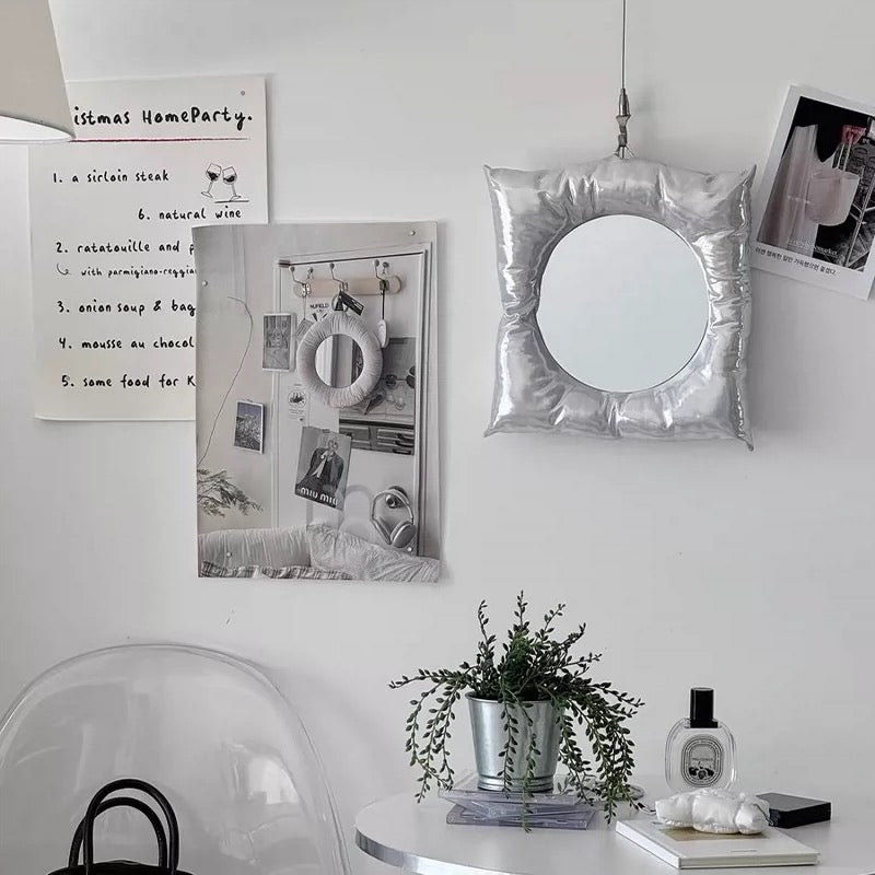 Decorative wall with mirror, photos, and plants in a home setting