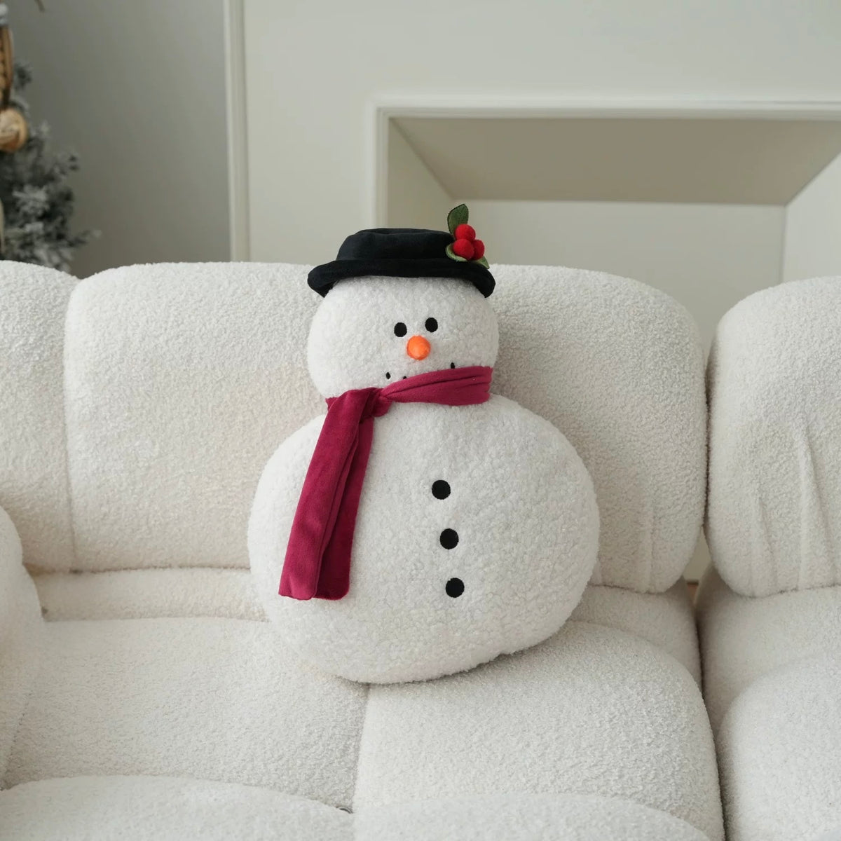 Snowman decorative Christmas pillow with dark hat and burgundy scarf displayed on a light chair